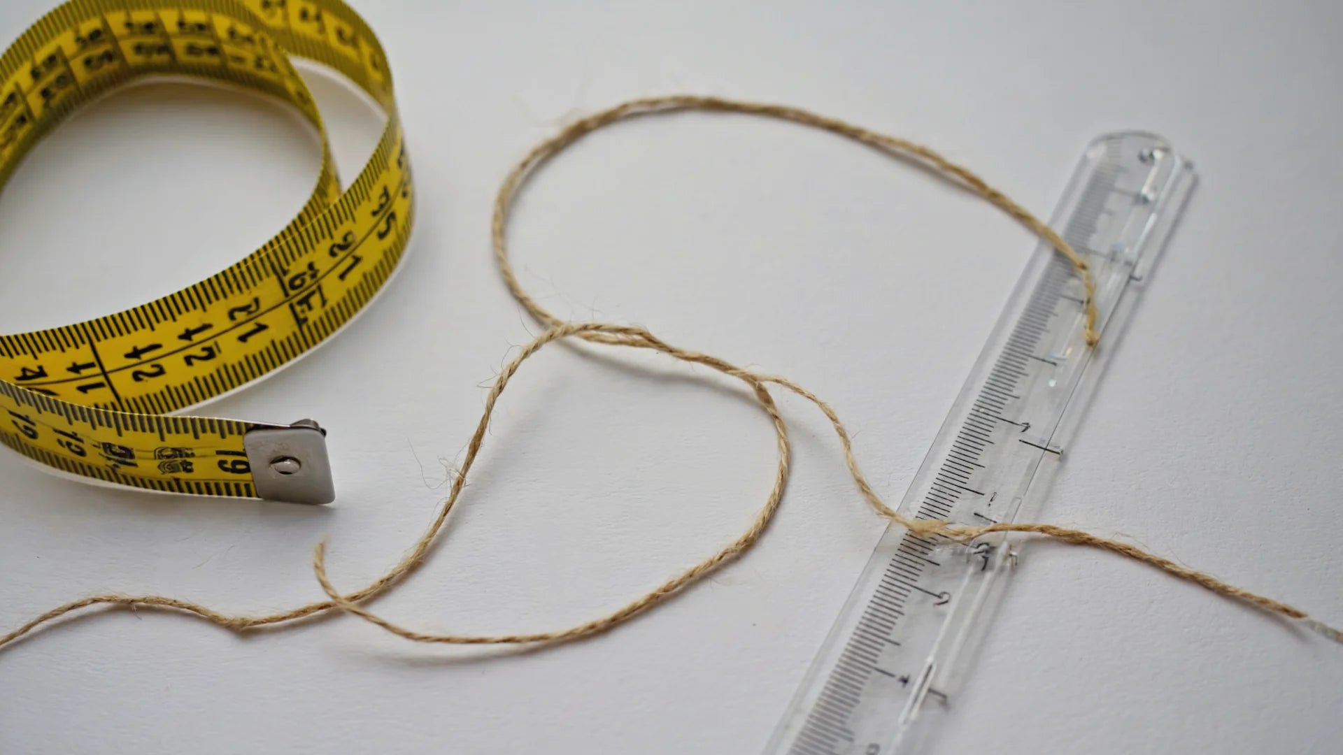 On a table, there is a soft tape measure, a rope, and a rigid ruler.
