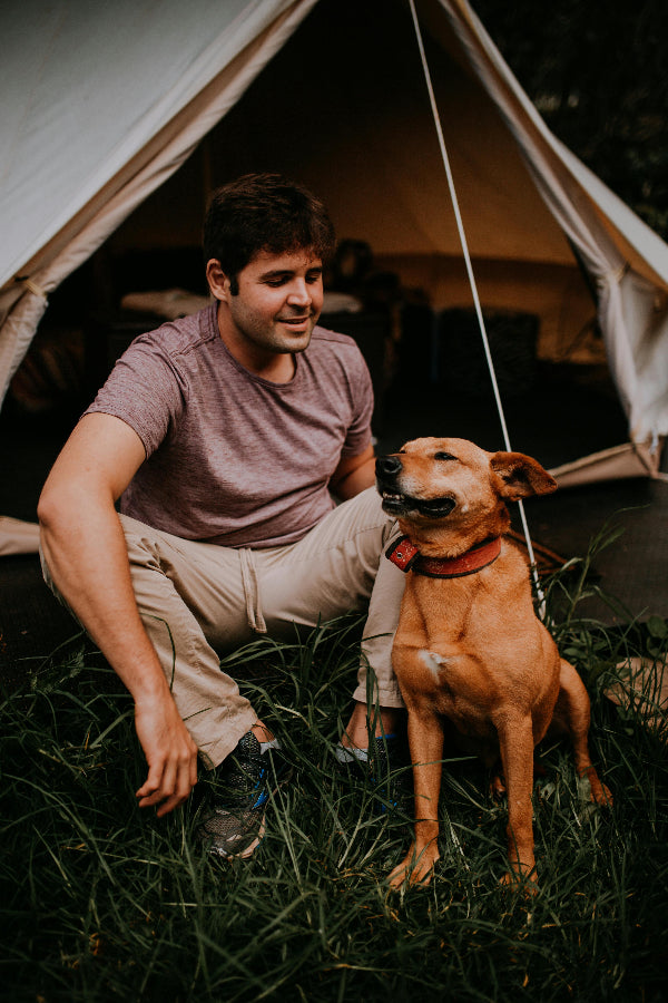 Man sitting with a dog in front of a tent
